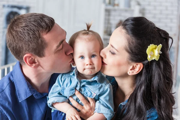 Мать и отец целуют свою годовалую дочь — стоковое фото