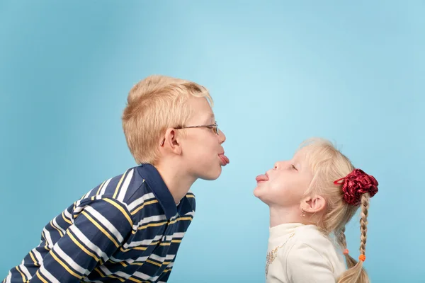 Teenage boy and girl stick out tongues to each other — Stock Photo, Image
