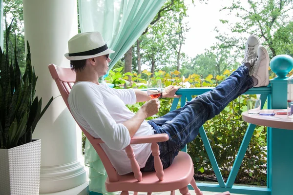 Hombre de sombrero blanco y copa de vino descansando en terraza —  Fotos de Stock