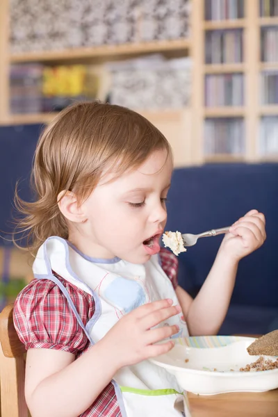 Liten jente som spiser grøt hjemme – stockfoto