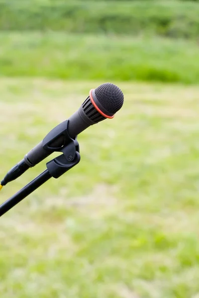 Микрофон в воздухе над зеленой травой — стоковое фото