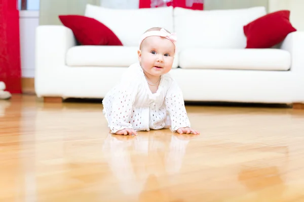 Glückliches acht Monate altes Mädchen, das auf einem Hartholzboden kriecht — Stockfoto