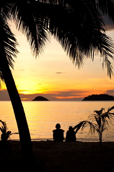 Silhouette d'un couple romantique assis sur une plage au coucher du soleil — Photo