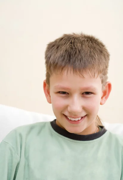 Adolescent souriant assis sur un canapé blanc — Photo