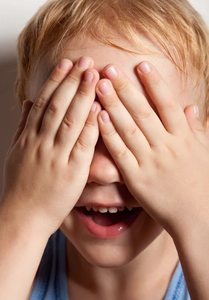 Porträt eines glücklichen kleinen Jungen, der seine Augen mit Händen bedeckt — Stockfoto