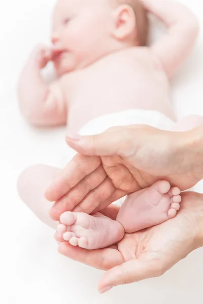 Madre sostenga suavemente las piernas de la niña en las manos — Foto de Stock