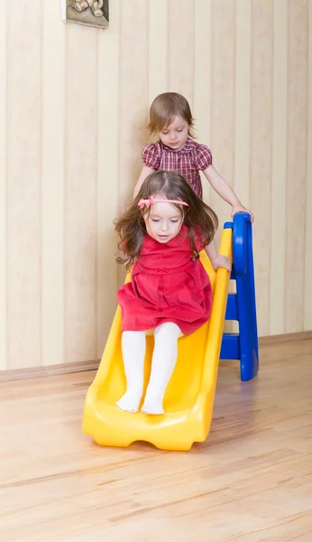Two adorable girls having fun atop playground slide — Stock Photo, Image