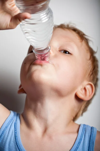 Le garçon boit de l'eau minérale. — Photo