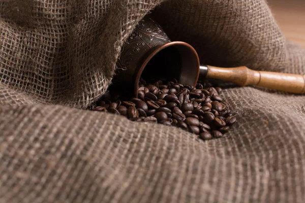 Cezve with freshly roasted coffee beans on sackcloth Stock Image