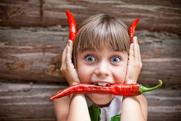 Chica con un chile rojo picante en la boca muestran cuernos de diablo Imagen De Stock