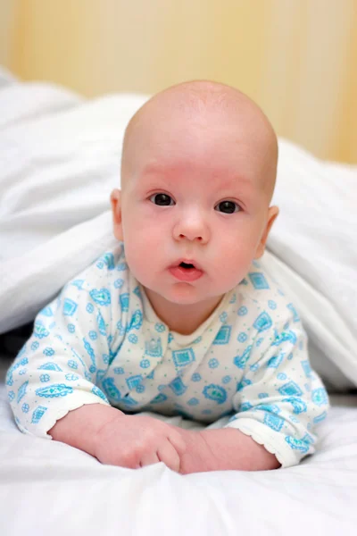 Surprised baby lie on tummy and look forward Stock Picture