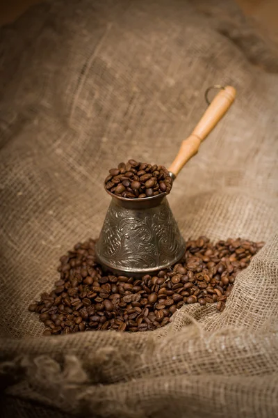 Cezve med nyrostat kaffe bönor på säckväv Stockfoto