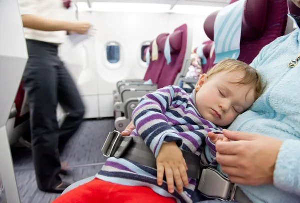 Мать и спящая двухлетняя девочка путешествуют на самолете Лицензионные Стоковые Фото