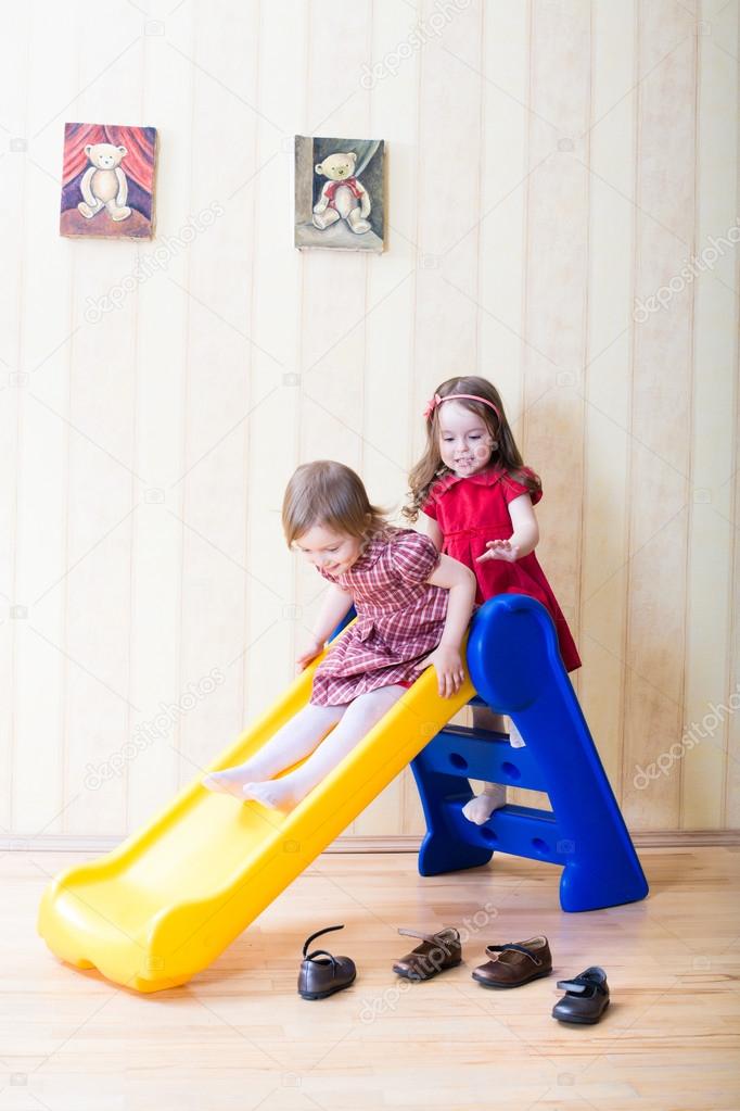 Two adorable girls having fun atop playground slide 