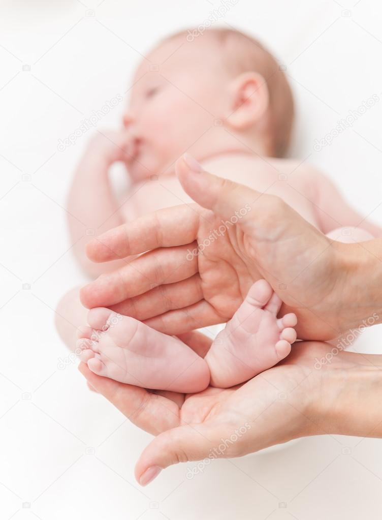 Mother gently hold baby girl legs in hands