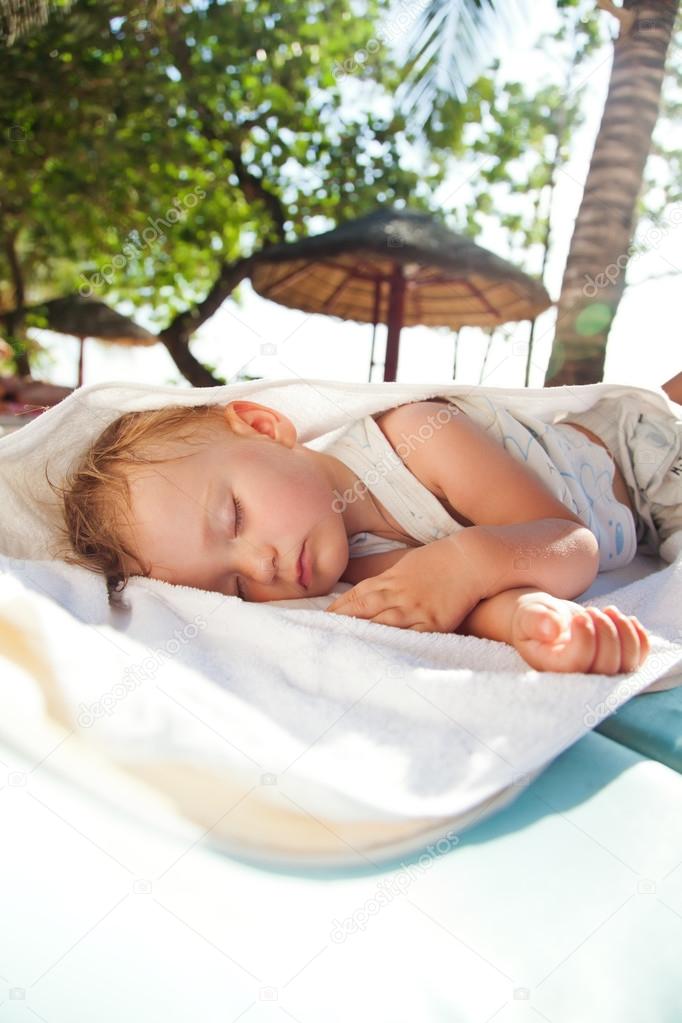 Little baby girl asleep on a chaise lounge outdoors in the shade