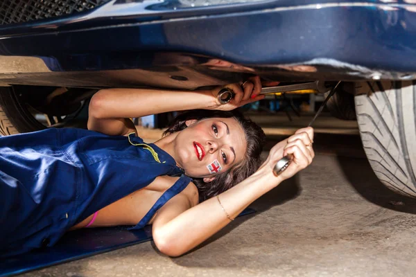 Mujer comprueba la suspensión del coche en servicio . — Foto de Stock