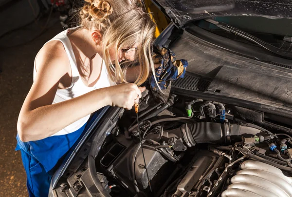 Chica comprueba el nivel de aceite en el coche — Foto de Stock