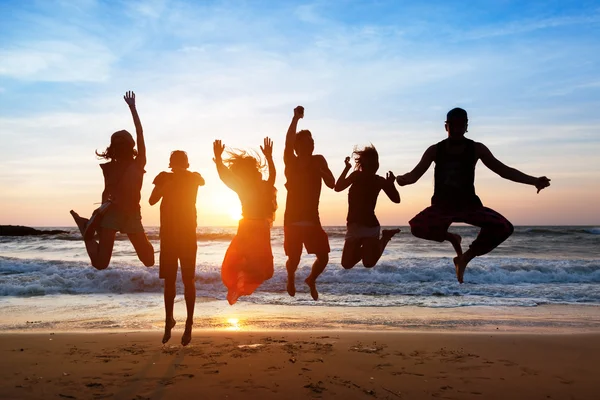 Seis pessoas pulando na praia ao pôr do sol . — Fotografia de Stock