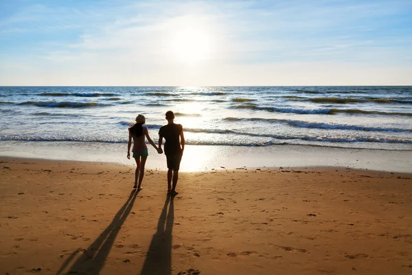 若いカップルがビーチを歩いていて ストック写真