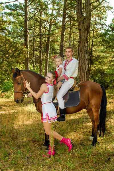 Ukrajinci máma a táta dcera jezdí v lese na koních — Stock fotografie