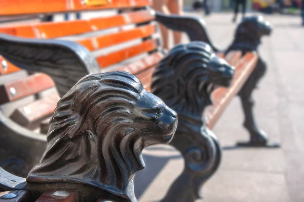 Скамейка в парке с чугунными ногами в виде головы льва — стоковое фото