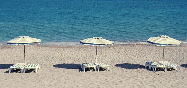 Liegestühle und Sonnenschirme am Strand von Kefalos — Stockfoto