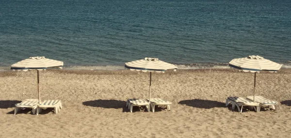 Liegestühle und Sonnenschirme am Strand von Kefalos — Stockfoto