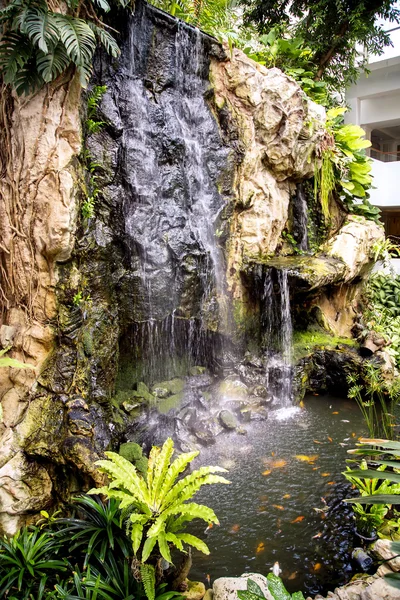 Small waterfall and pond with a koi carps fish — Stock Photo, Image