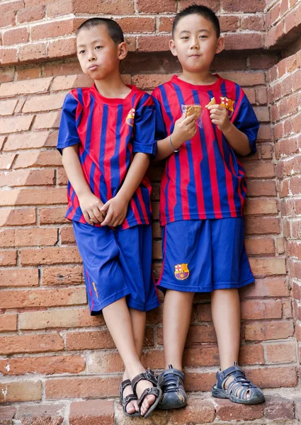 Twee jonge Aziatische kind in de vorm van de nationale ploeg van Barcelona — Stockfoto