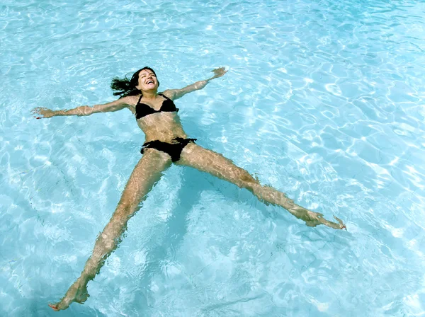 Treinamento de menina sorridente em uma piscina exterior de água azul-turquesa — Fotografia de Stock