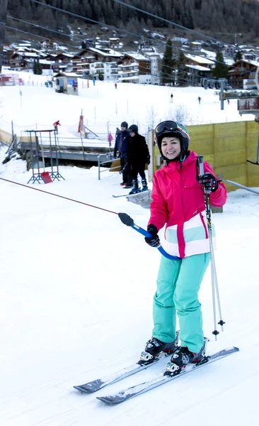 Smiling woman with ski suit going up t-bar while skiing