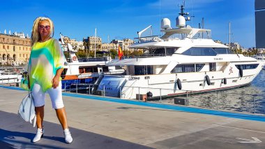 İspanya, BARCELONA, SEPTEMBER, 2020 - Vell, Barcelona 'da lüks bir okyanus yatının arka planında yaz elbisesi giymiş ince bir kadın