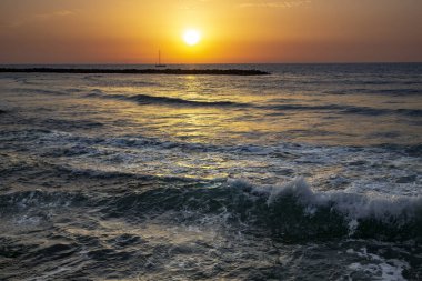 Günbatımında Tel Aviv, İsrail 'deki Akdeniz üzerinde turuncu tonlarda yelkenli sürüyor.