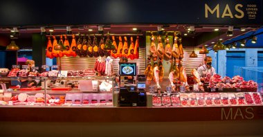İspanya, BARCELONA, MARCH, 2021 - İspanyol satıcı Barcelona, İspanya 'daki La Boqueria Market' te iberico ve Serrano jamon satıyor.