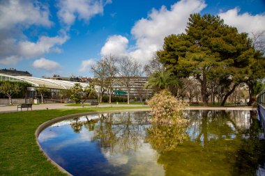 Barselona, İspanya sakinleri için dinlenme yerinde bulutlu mavi gökyüzüne karşı küçük bir göleti olan güzel bir park.