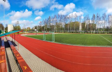 LATVIA, RIGA, APRIL, 2021 - Riga, Letonya 'da kale ve suni sahası olan koşu pistleri ve futbol sahası olan stadyum. Koşu pisti, atletizm için yapay bir koşu alanıdır..