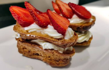 Çilek dilimleriyle süslenmiş kremalı pasta. Meyvelerle süslenmiş kek..