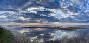 Baltık Denizi 'nin sıcak körfezinin panoraması günbatımında kümülüs bulutlarının arka planına karşı. Letonya 'daki Riga Körfezi kıyıları turistler arasında popülerdir..