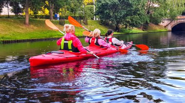 LATVIA, RIGA, JULY, 2021 - Aktif insanlar Letonya 'nın başkenti Riga şehir kanalında kano kullanmaktan keyif alıyorlar. Turistler kanoyla geziyor.