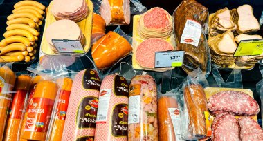 LATVIA, RIGA, JULY, 2021 - Çeşitli türde tütsülenmiş et jambonu otlar ve sosislerle birlikte. Şişman abur cubur. Obezite konsepti. Fazla kilolu. Kasap dükkanında tütsülenmiş et var..