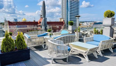 Restoranın beyaz hasır mobilyalı açık verandası ve Letonya 'nın başkenti Riga Eski Kasabası' nın çatıları manzaralı.