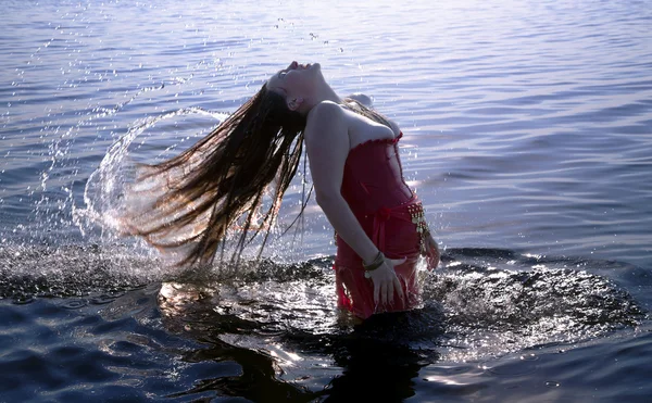 Jonge vrouw doen een haar van water splash in zee — Stockfoto