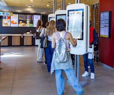 LATVIA, RIGA, SEPTEMBER, 28, 2025: İnsanlar Letonya 'daki Riga alışveriş merkezindeki McDonald' s 'ın elektronik menü bölümünden sipariş veriyor. Dünyanın en büyük fast food zinciri..