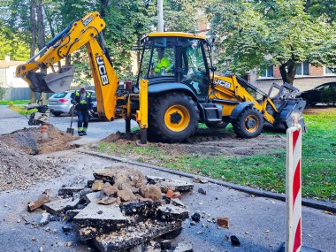 LATVIA, RIGA, SEPTEMBER 20, 2025: JCB kazıcılı bir işçi Letonya 'nın başkenti Riga' daki şehir yollarında onarım çalışması yürütüyor.