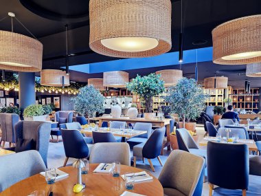 LATVIA, RIGA, ECTOBER, 29, 2025: Ahşap mobilyalar, hasır avizeler ve limon ağaçları ile dolu samimi bir iç mekan Riga, Letonya 'da bir İtalyan restoranında.