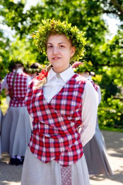 LATVIA, RIGA, JULY, 15, 2025: Letonya 'nın Riga, Letonya' daki Özgürlük Anıtı yakınlarındaki ulusal bir kostüm içindeki folklor grubundan bir kız