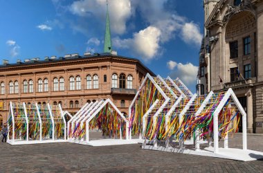 LATVIA, RIGA, 17 Ağustos 2025: Letonya 'nın başkenti Riga' nın 824. doğum günü kutlamaları için Riga Eski Kasabası 'ndaki Kubbe Meydanı' nda renkli kurdeleli ahşap yapılar.