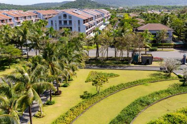 Vietnam, Phu Quoc, 5 Ocak 2026: Vietnam 'ın Phu Quoc kentindeki Novotel' in bahçesinde çiçek açan çalılar ve uzun palmiye ağaçları ile manikürlü çimenler