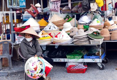 Vietnam, Hanoi, 23 Aralık 2025: Vietnamlı bir kadın Hanoi, Vietnam 'da bir pazarda saman koni şapkası satıyor.